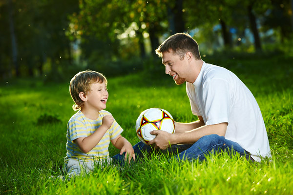 Father and son with a soccer ball in the grass